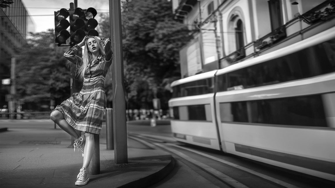 fotografia di moda di una modella in posa vicino a un tram di passaggio.