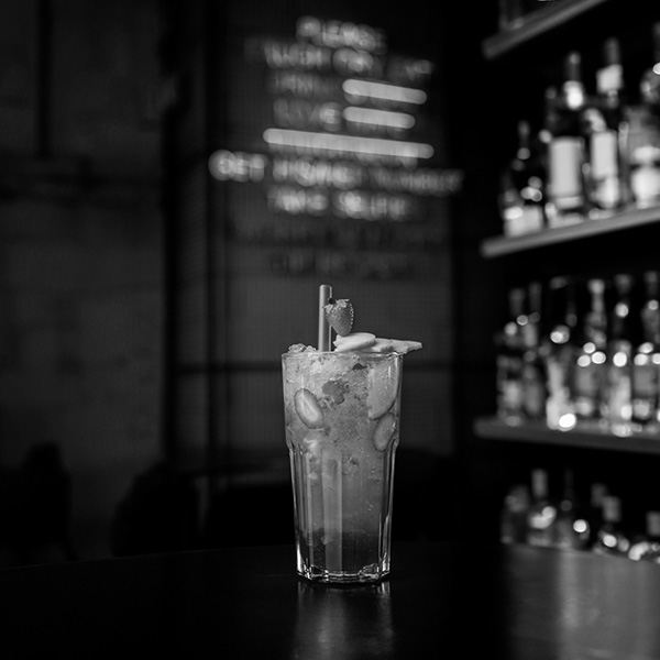 Immagine in bianco e nero di un cocktail in un bar utilizzato come immagine di copertina del servizio fotografico di cibo e bevande.